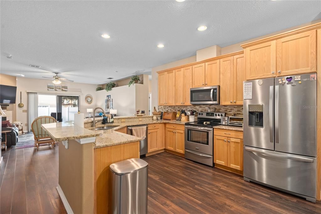 KITCHEN WITH UPGRADED HARDWOOD CABINETS, CUSTOM BACKSPLASH, GRANITE COUNTERTOPS AND STAINLESS STEEL APPLIANCES. FLOOR IS LUXURY VINYL PLANKING.