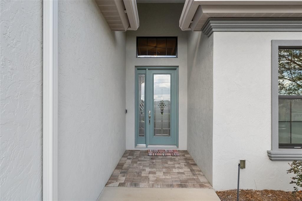 The exterior entry features a pavered walkway and upgraded leaded glass entry door.