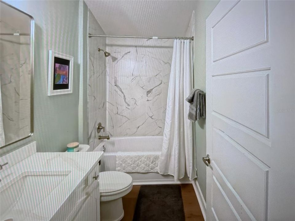 guest bathroom features quartz countertop and tiled tub/shower