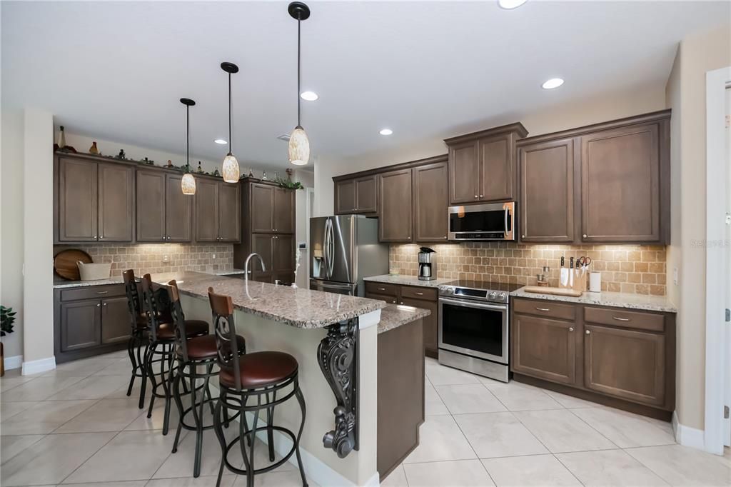 spectacular kitchen with island, backsplash, under lighting ,stainless appliances and granite