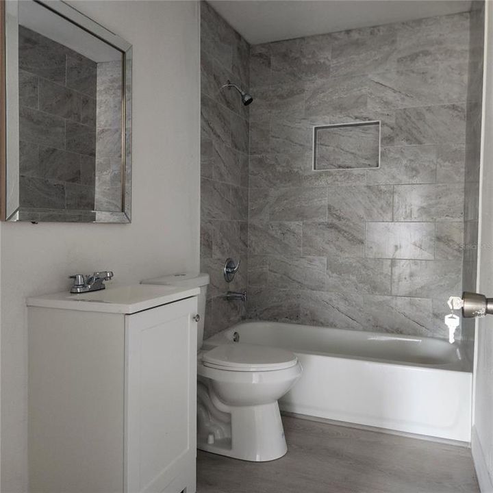 Brand new bathroom, designer tile installed to the ceiling and offers a built in shampoo shelf.