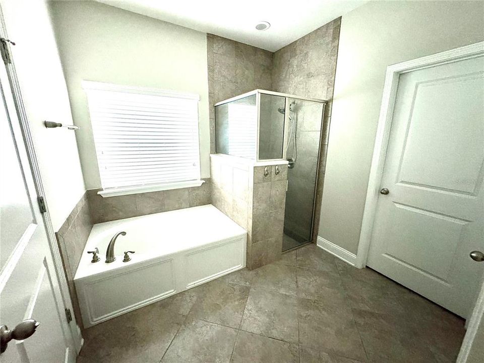 Master bathroom ensuite with dual sinks, soaking tub, shower and separate toilet room