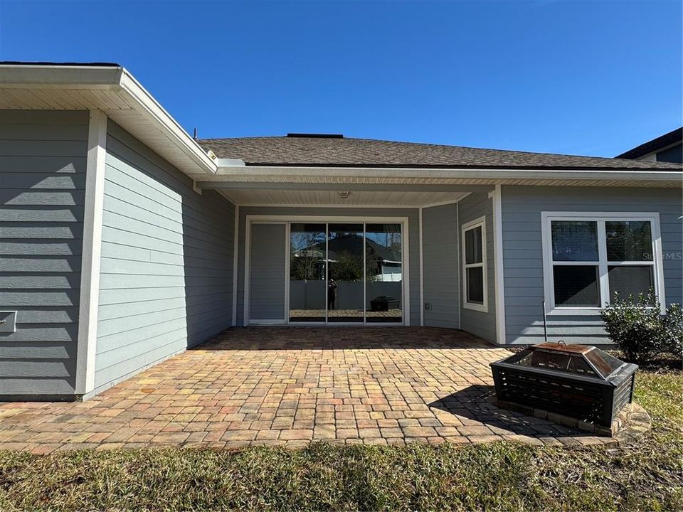 Back of home and covered Lanai area with fire pit