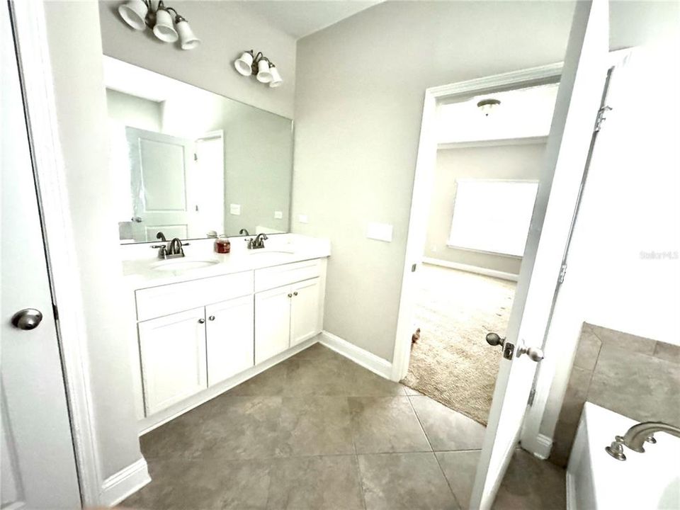 Master bathroom ensuite with dual sinks, soaking tub, shower and separate toilet room