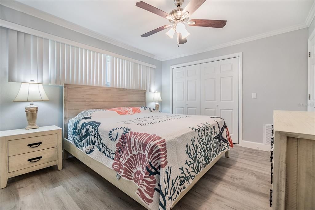 Step into this inviting bedroom featuring elegant finishes, a neutral color palette, and abundant natural light. The spacious layout includes a ceiling fan for comfort, stylish laminate wood flooring, and ample closet space, creating a serene retreat for relaxation.