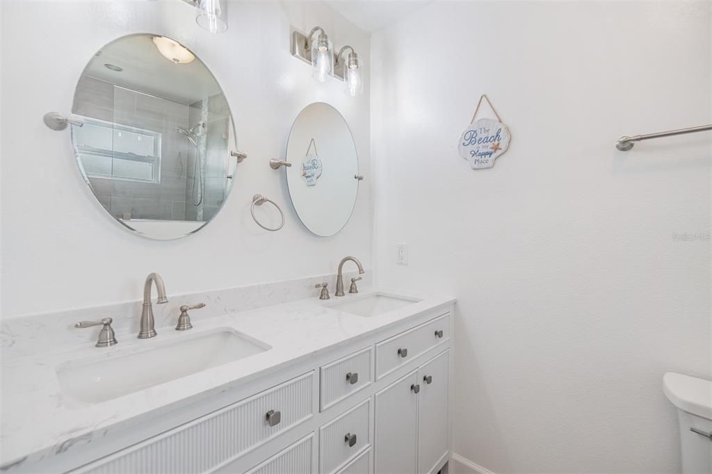 Step into this beautifully updated bathroom featuring a modern double vanity and elegant brushed nickel fixtures. The dual round mirrors add a touch of sophistication, while the clean white palette creates a bright and refreshing space. With stylish finishes and thoughtful design, this bathroom offers both functionality and luxury.