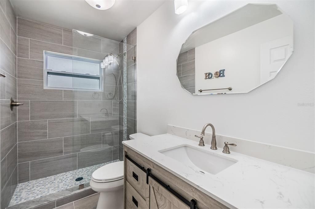 This beautifully remodeled bathroom features a modern walk-in shower with stylish floor-to-ceiling tile and a sleek frameless glass enclosure.