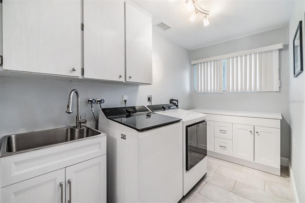 Enjoy the convenience of this spacious and well-appointed laundry room, featuring ample cabinetry for storage and a sleek utility sink for added functionality.