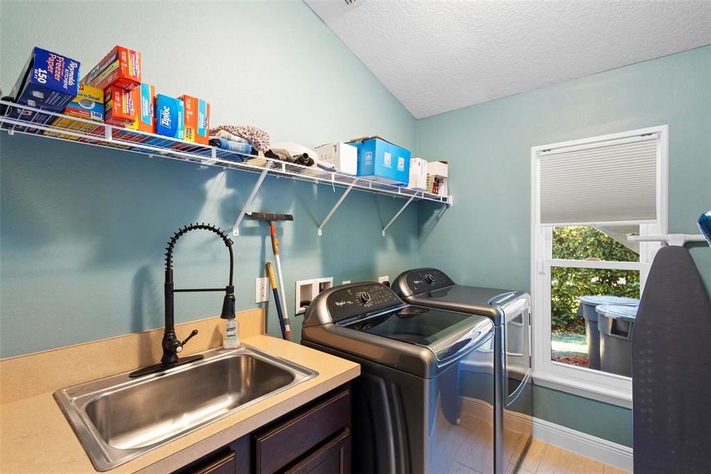 The indoor laundry room includes a utility sink and the washer and dryer stay with your new home.