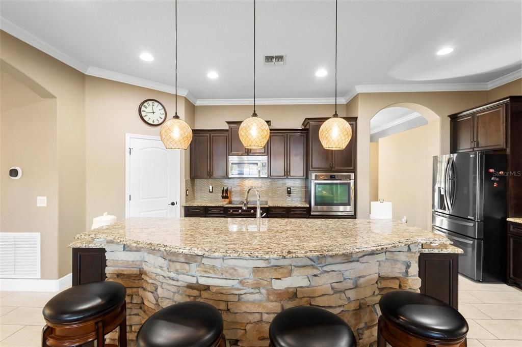 The breakfast bar features beveled granite edges and decorative stone.