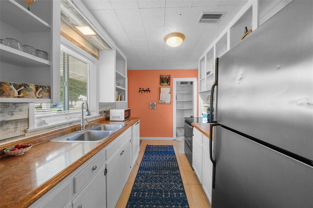 Long galley kitchen with attractive backsplash and built-in pantry for additional storage space