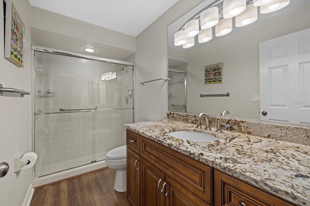 Full guest bathroom with easy walk-in tiled shower, granite counter, and plenty of vanity storage.