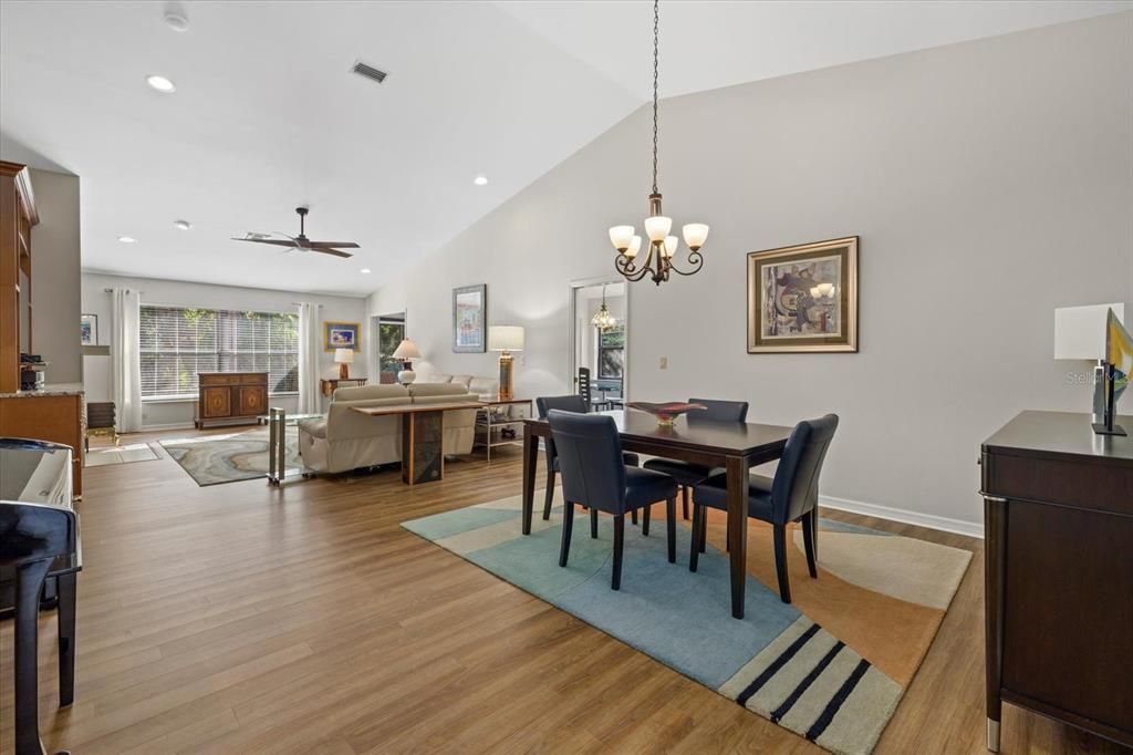 Open floor plan with dining and living rooms features vaulted ceilings.