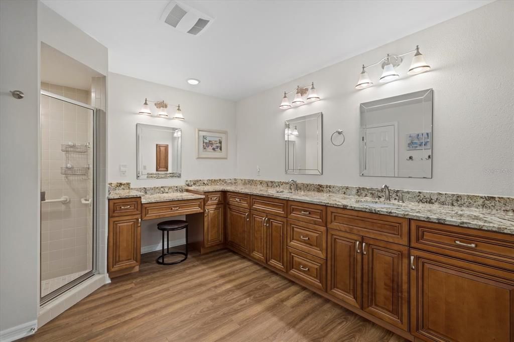 This roomy bathroom provides a comfortable, open atmosphere with double sinks, a separate water closet and walk-in tiled shower.