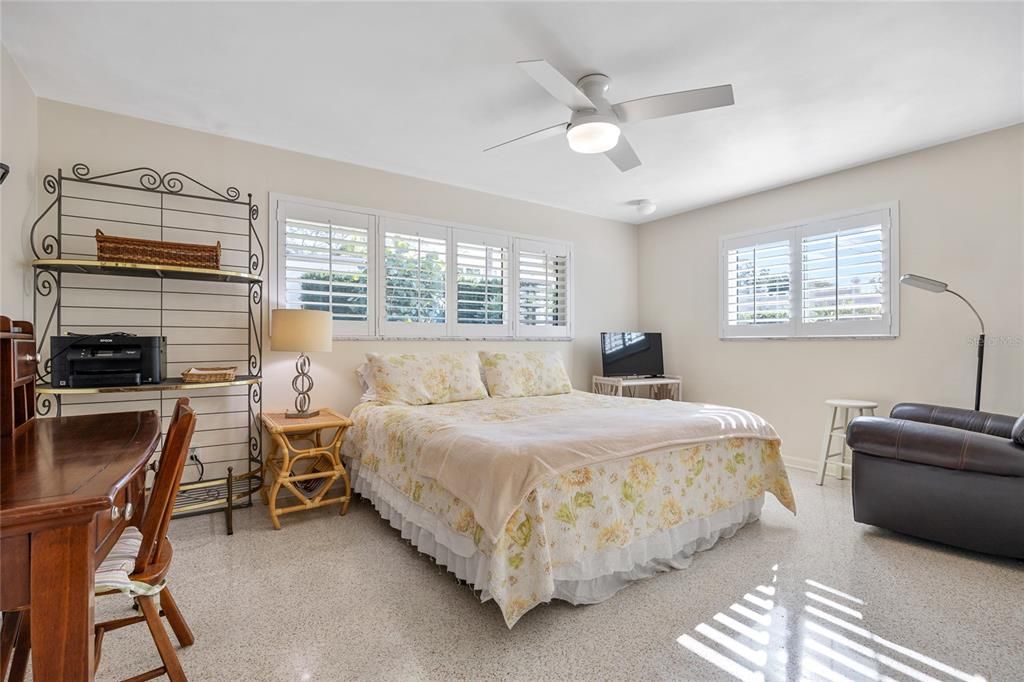 This guest bedroom is quite spacious and has gorgeous terrazzo flooring and plantation shutters on the windows