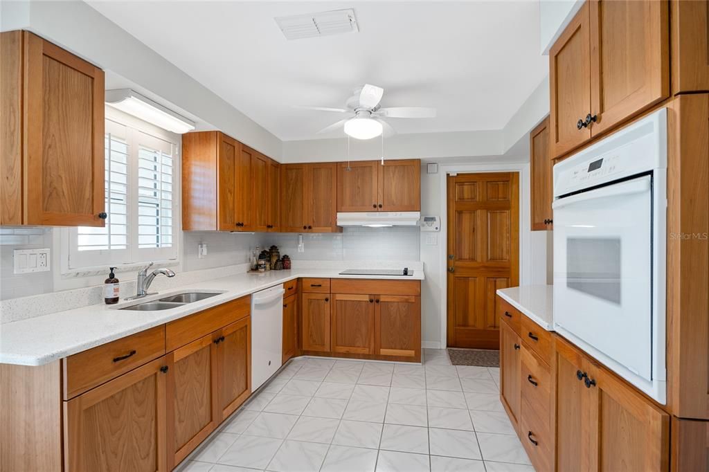 This gorgeous kitchen features warm shaker style cabinets and beautiful quartz counters with a subway tile backsplash.