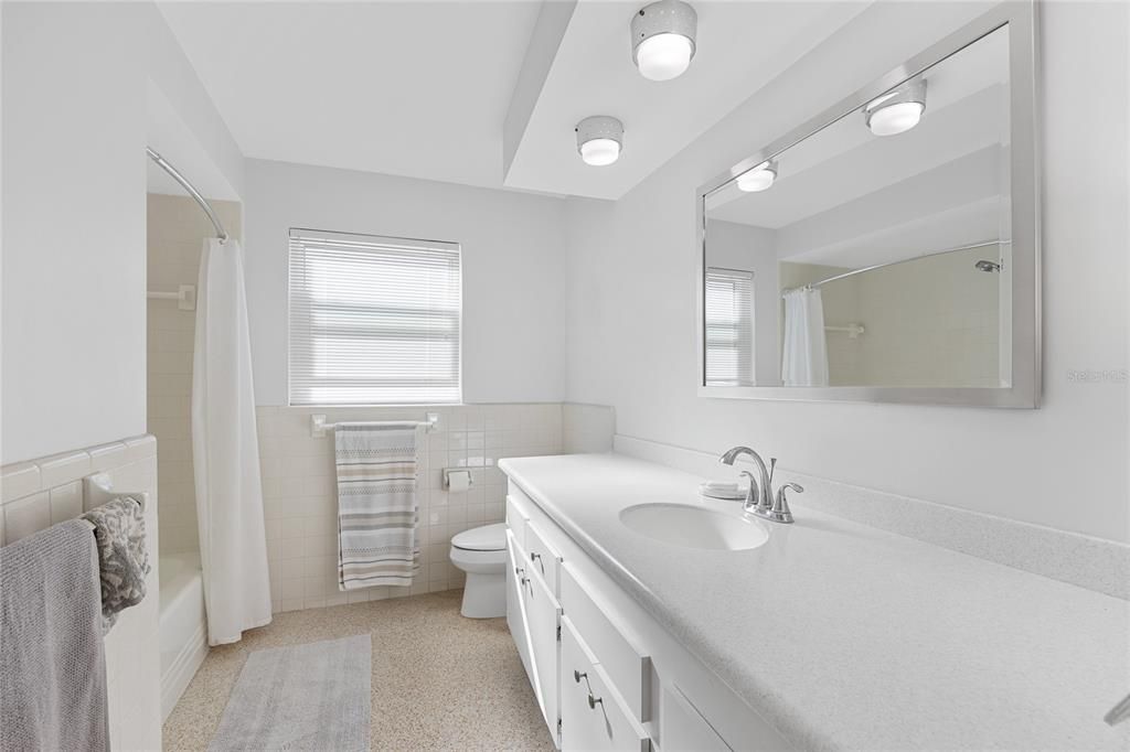 The guest bathroom has beautiful terrazzo flooring and recent improvements include a new counter, sink and faucet as well as having the tub and tile reglazed.