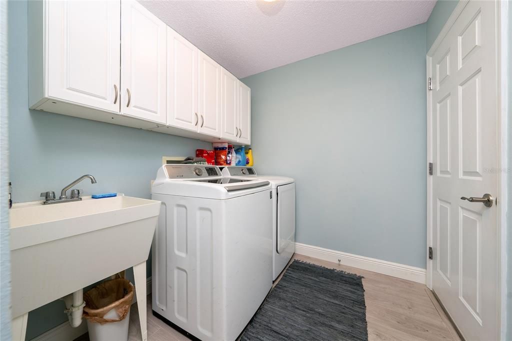 Indoor laundry area with sink and upper cabinets, accessible from foyer and leads to the garage.