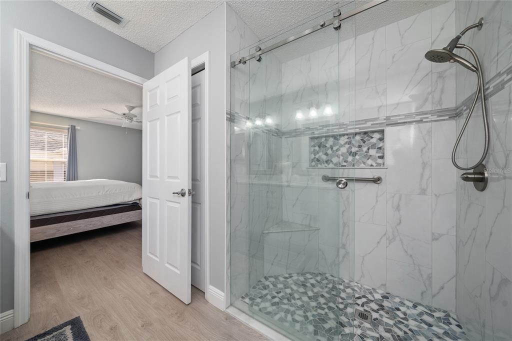 Beautiful ensuite has a glass door walk-in shower with custom decorative tiles.