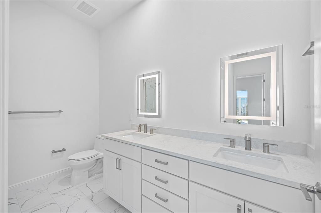 Guest Bath with double vanities, wood cabinetry and lighted vanity mirrors