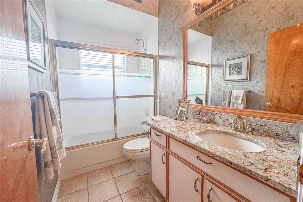 Bathroom 3 features a tile floor, a tub with shower and a mirrored vanity with storage.