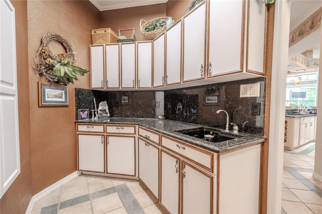 The laundry room has built-in cabinetry, granite counters and a sink.