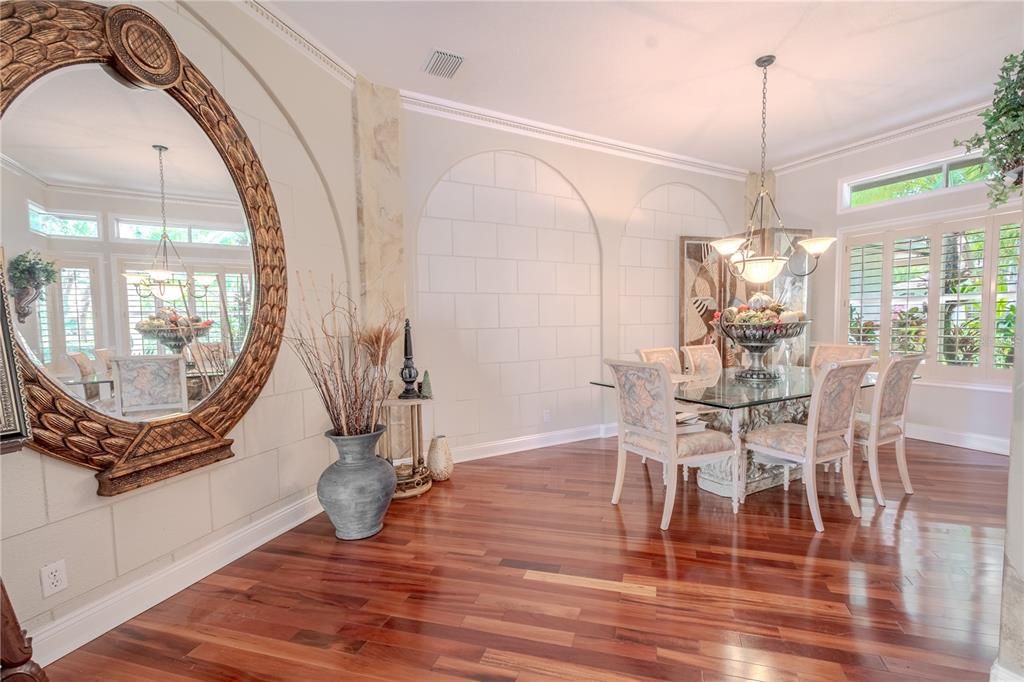 The dining room features architectural elements, molding, a chandelier and a picture window with shutters and a transom window.