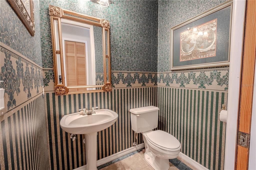 The half bath has a tile floor and a mirrored pedestal sink.