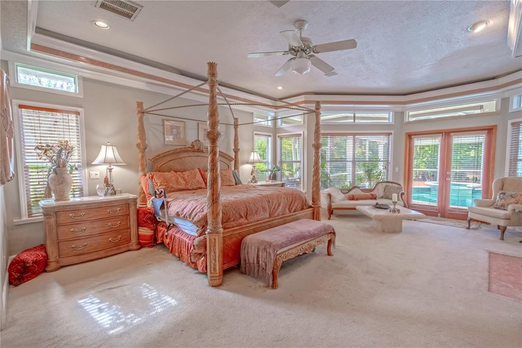 The primary bedroom features a tray ceiling, ceiling fan, bay window, transom windows and french doors that open to the lanai.