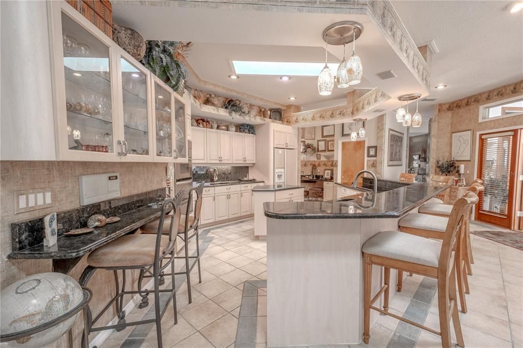 The kitchen features a breakfast bar with granite countertops and artistic glass pendant lights.