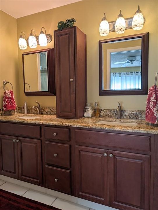 Renovated primary bath features raised vanity with double sinks, granite countertops, new mirrors, light fixtures and brushed nickel hardware.