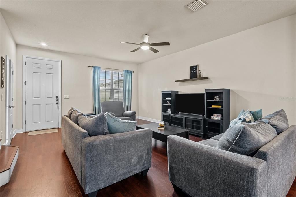 Living Room with upgraded laminate floor, half bath, stair, and entry on the left of this photo