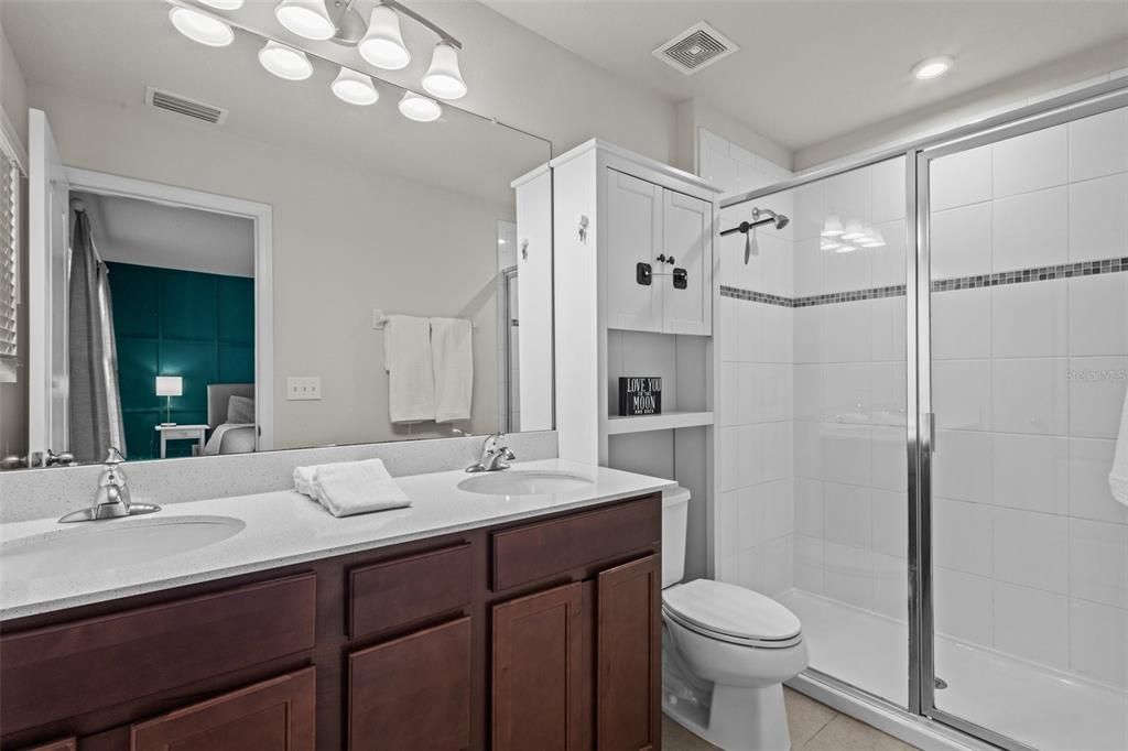 En Suite Bathroom with quartz countertops, dual sinks, and a walk in shower