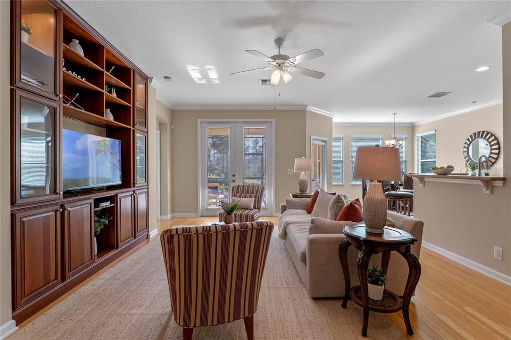 Great Room w/ a custom built-in entertainment center & French doors to expanded screen lanai