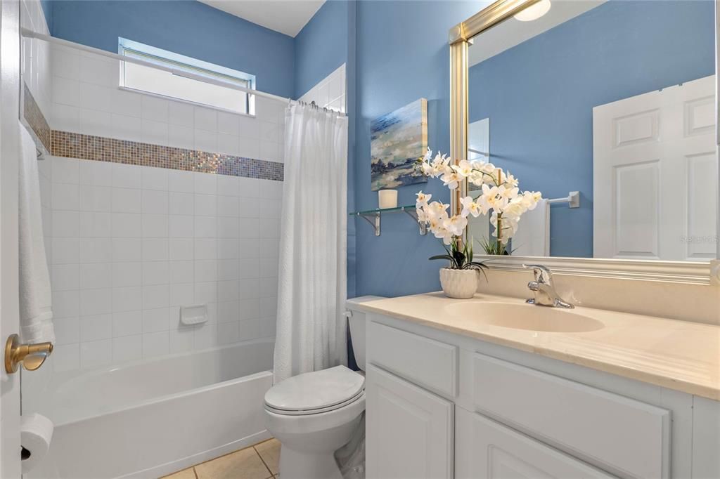 Guest Bathroom w/ framed mirror above vanity & tub/shower combo