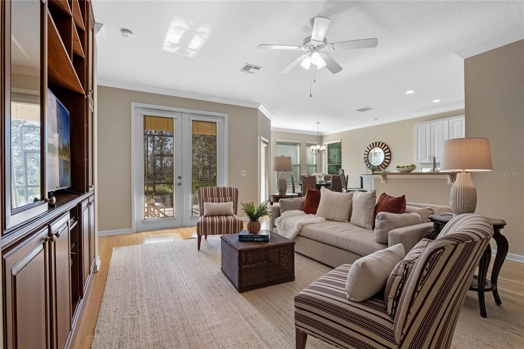 Great Room w/ a custom built-in entertainment center & French doors to a screened lanai overlooking a conservation area