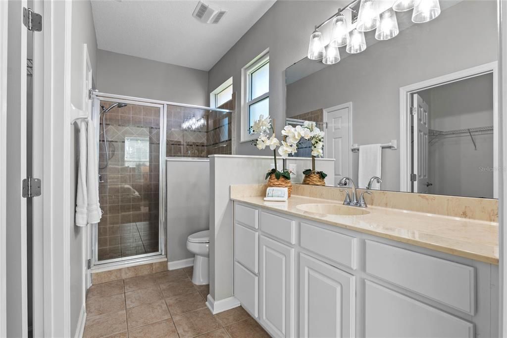 Primary Bathroom w/ glass enclosed walk-in shower, bench seat & raised height vanity