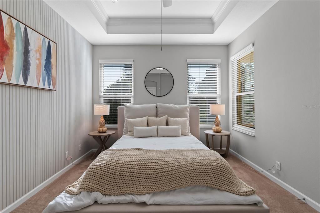 12' x 15' Primary Bedroom w/ Wainscot paneling, tray ceiling, crown molding & a ceiling fan