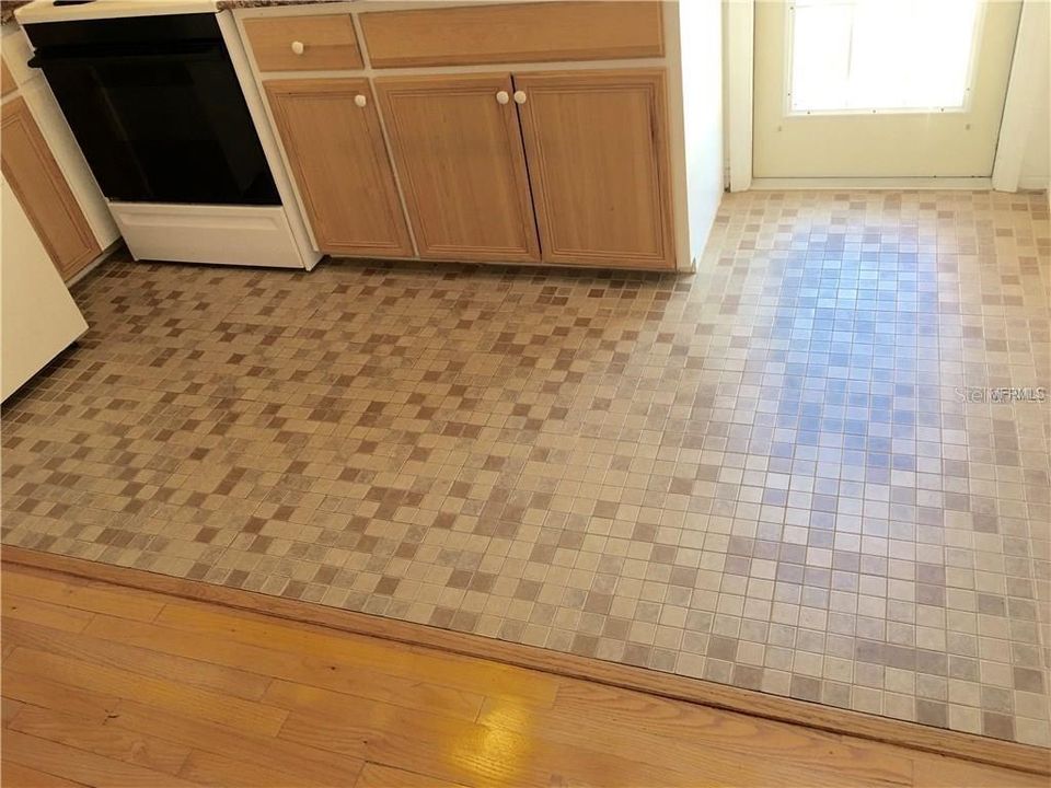 Tile floor in kitchen with back door that leads to the parking space just outside