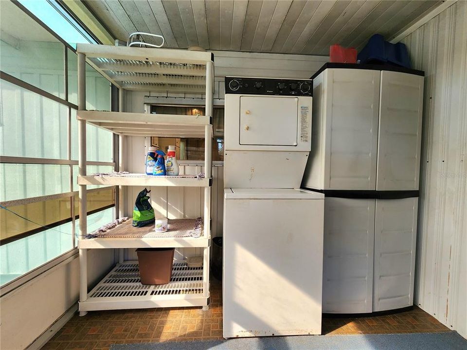 Raised enclosed screen room with stack washer/dryer.