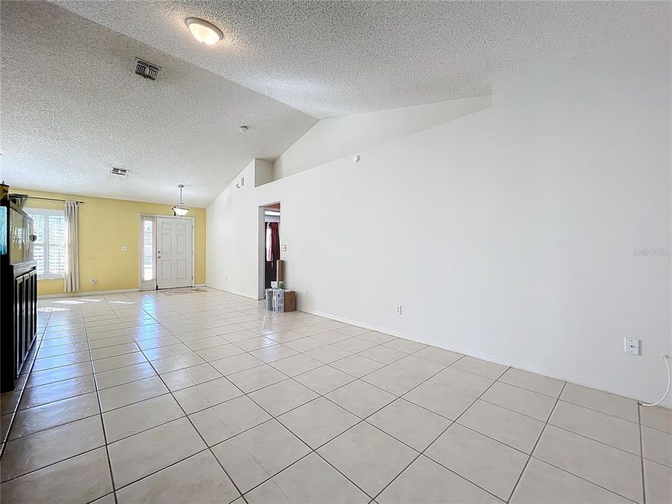 The living room with high vaulted ceilings and a plant shelf for your favorite home decor.