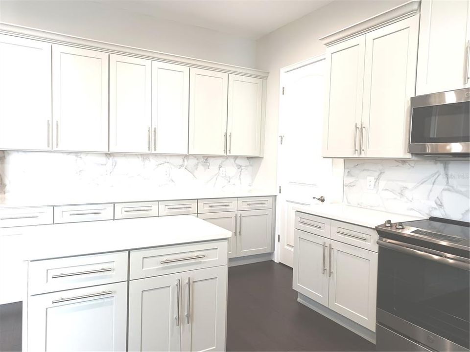 Kitchen island, light grey cabinets and quartz counters