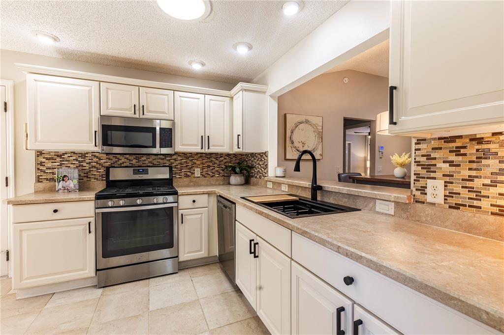 TO THE LEFT IS YOUR SPACIOUS EAT-IN KITCHEN WITH WHITE CABINETRY WITH OVER AND UNDER CABINET LIGHTING