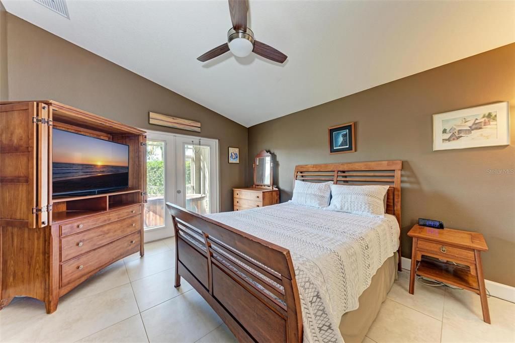 Primary bedroom - can we just say wow!  Vaulted ceilings, warm colors and great space.  Tile floors, French doors to the enclosed lanai with it's own full bath.