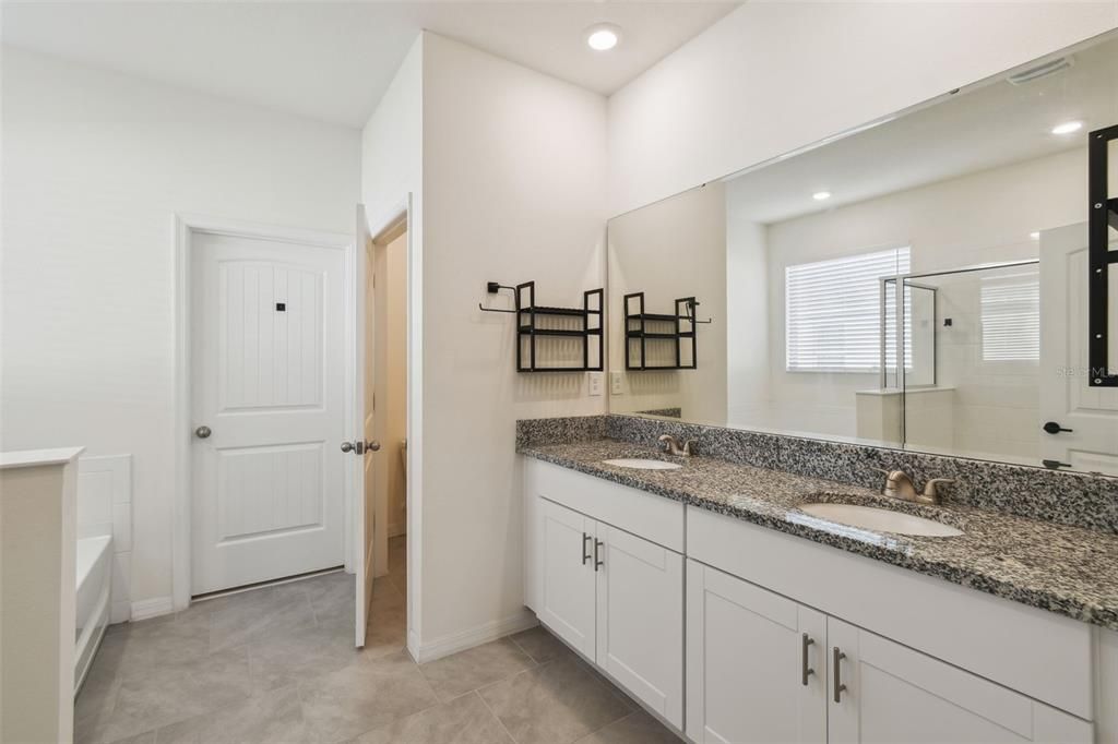 The primary bathroom features a double vanity, a private toilet area, a walk-in closet, a garden tub, and a separate shower.