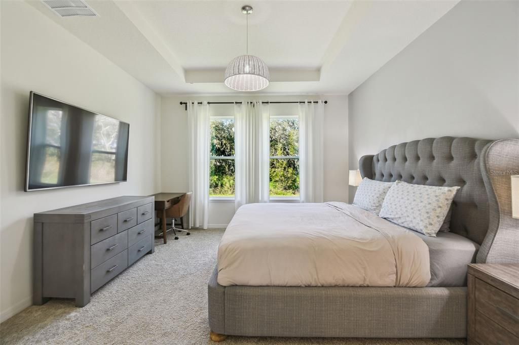 The primary bedroom features a tray ceiling and offers a lovely view of the beautiful backyard.