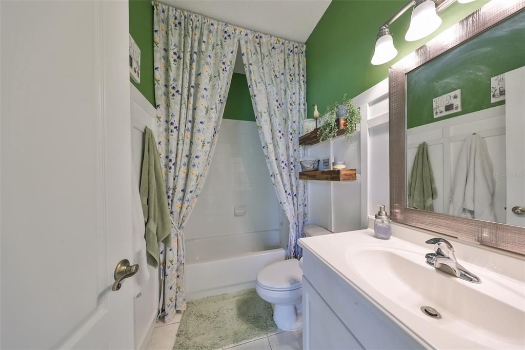 The guest bathroom has a single vanity sink and a tub/shower with porcelain tile.