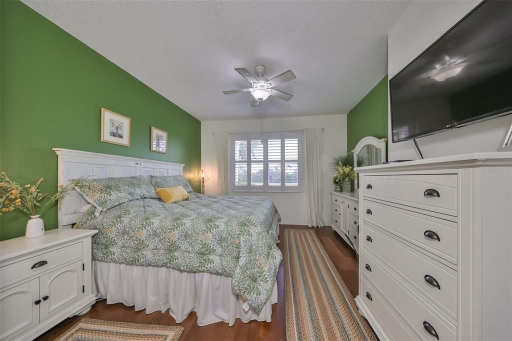 Primary Bedroom has plenty of space for furniture and an additional seating chair with lovely engineered hardwood floors and plantation shutters.