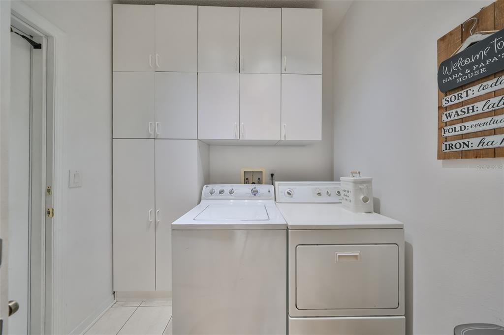 This indoor laundry room has a washer and dryer, as well as tons of storage space for cleaning supplies.