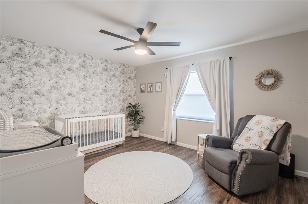 Second bedroom with luxury vinyl planks and ceiling fan.